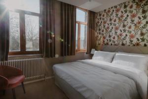 a bedroom with a large bed with a floral wallpaper at Château de Looz in Borgloon