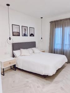 um quarto branco com uma grande cama branca e uma janela em Apartamento Domus em Teruel