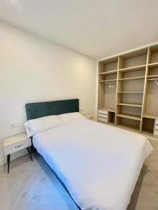 um quarto com uma grande cama branca e prateleiras em Apartamento Domus em Teruel