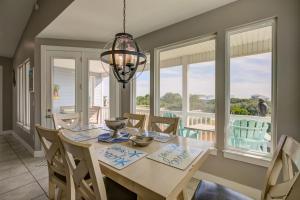 una sala da pranzo con tavolo, sedie e lampadario pendente di Coastal Haven by Vacation Homes Collection a Gulf Shores