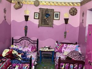 a room with two beds and a purple wall at Arafa Nubian Guest house in Aswan
