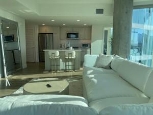a living room with a white couch and a kitchen at Extraordinary Escape with Rooftop Pool 2 in San Diego