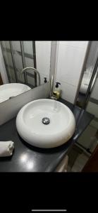 La salle de bains est pourvue d'un lavabo blanc et d'un miroir. dans l'établissement Apartamentos Gran Via Musicales, à Madrid