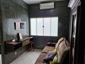 Zimmer mit Sofa, Schreibtisch und Fenster in der Unterkunft Apartamento inteiro em condomínio in Rio Branco