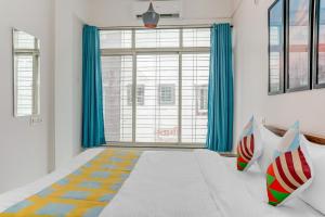 a bedroom with a large window with blue curtains at OYO Home Dazzling Studios Near Airport Near Pune Airport in Lohogaon