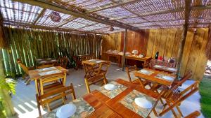 a restaurant with wooden tables and wooden chairs at Pousada Kiarô Caraíva in Caraíva