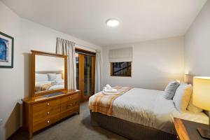 a bedroom with a bed and a dresser and a mirror at Sun-filled on Wakatipu - New Queenstown Listing in Queenstown