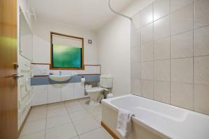 a bathroom with a tub and a toilet and a sink at Sun-filled on Wakatipu - New Queenstown Listing in Queenstown
