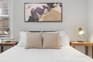 een slaapkamer met een bed met witte lakens en 2 lampen bij Elegant & Stylishly 1BR Fully Furnished Apt - Lincoln 205 in Chicago