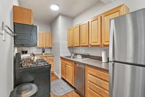 a kitchen with wooden cabinets and a stainless steel refrigerator at Elegant & Stylishly 1BR Fully Furnished Apt - Lincoln 205 in Chicago