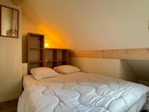 Charmant duplex pour 2/3 pers في كوتيريه: سرير مع وسادتين في غرفة
