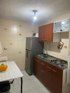 eine Küche mit einem Kühlschrank, einer Spüle und einem Tisch in der Unterkunft El apartamento de Mario in Bogotá