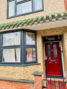 a brick house with a red door and windows at The Great Falcon Accommodation in London