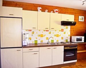 a kitchen with white cabinets and a sink and a refrigerator at Haus Tonelehof in Dellach im Drautal