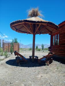 a large umbrella and lounge chairs in the desert at Cabañas Angualasto in Uspallata