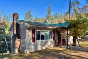 a small white house with a green roof at Red Door Cottage Fireplace bbq 12 mi to Yosemite in Oakhurst