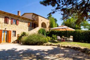 a stone house with a table and an umbrella at Poggio Cantarello Vacanze in Chiusi