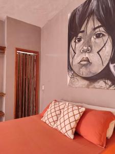 a bedroom with a painting of a woman on the wall at Pousada Kiarô Caraíva in Caraíva