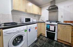 a kitchen with a washing machine and a microwave at *RA1GH* For your most relaxed & Cosy stay + Free Parking + Free Fast WiFi * in Bramley