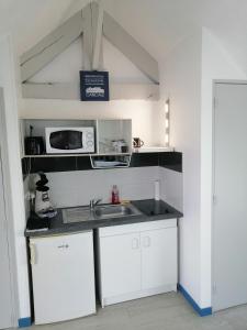 eine Küche mit einer Spüle und einer Mikrowelle in der Unterkunft Studio 1 proche du port in Cancale