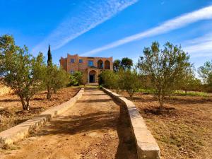 eine Schotterstraße, die zu einem großen Backsteingebäude führt in der Unterkunft Dar Zaouia , El Hanchane , Essaouira , Morocco 