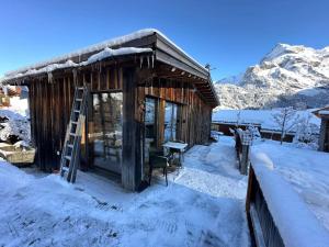 Una cabaña de troncos en la nieve con una escalera en Out of the Box, en Gsteig