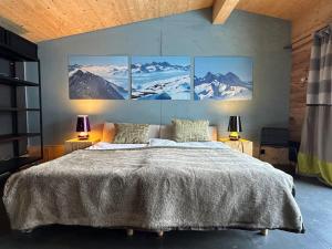 a bedroom with a large bed with three paintings on the wall at Out of the Box in Gsteig