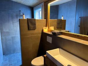 Un baño con lavabo, inodoro y espejo. en Out of the Box, en Gsteig