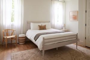 a white bedroom with a large bed and a chair at The Wendell House - Idyllic Designer Escape in Nashville