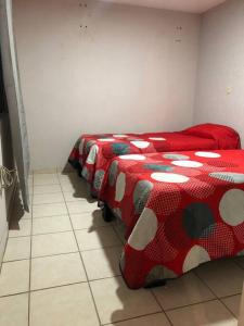 Duas camas num quarto com edredão vermelho e branco em Casa “Los Murales” em San José de Otates
