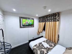 a bedroom with a bed and a tv on the wall at *RA1GH* For your most relaxed & Cosy stay + Free Parking + Free Fast WiFi * in Bramley