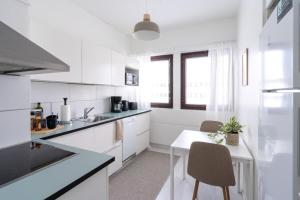 a white kitchen with a small table and chairs at Design apartment in city center with free parking in Rovaniemi