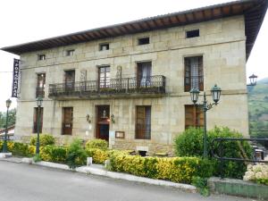 Edificio de piedra con ventanas y balcón en Hotel Posada del Pas, en Ontaneda