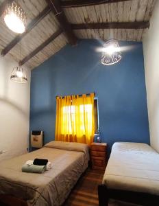 ein Schlafzimmer mit 2 Betten und einer blauen Wand in der Unterkunft Familia Albahaca in Tilcara