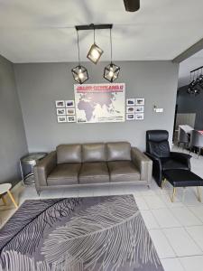 a living room with a leather couch and chairs at Globetrotter Condostay @ P11 in Putrajaya