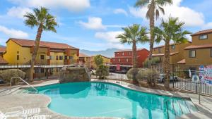 a swimming pool with palm trees and buildings at Golfer’s Oasis Condominium at Hawk Ridge in Mesquite