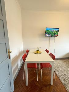 a white table with red chairs and a tv on the wall at Casas da Eva - Campolide in Lisbon