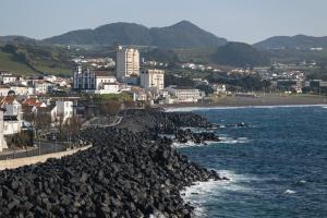 een rotsachtige kustlijn met een stad en de oceaan bij WelcomeBuddy - SeaLux Apartment in São Roque