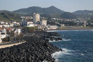 a rocky shoreline with a city and the ocean at WelcomeBuddy - SeaLux Apartment in São Roque