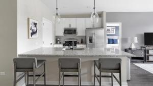 a kitchen with a counter with chairs around it at Landing Modern Apartment with Amazing Amenities (ID5350X87) in Warrenville