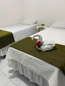 Serra de São Bento的住宿－Pousada Bouganville da Serra，两张床,配有白色床单和毛巾制成的天鹅