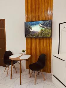 uma cozinha com uma mesa e duas cadeiras e uma televisão em Pousada Bouganville da Serra em Serra de São Bento