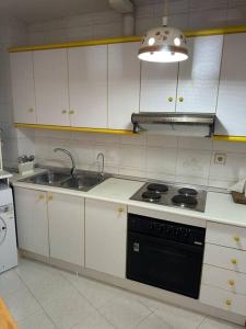 uma cozinha com armários brancos, um fogão e um lavatório em Casa en las buganvillas Vera Playa em Playas de Vera