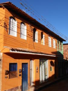 un edificio naranja con una puerta y ventanas azules en Casa de Gabi, en Lençóis
