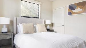 um quarto branco com uma cama com lençóis e almofadas brancos em Landing Modern Apartment with Amazing Amenities (ID1225X333) em Greenville