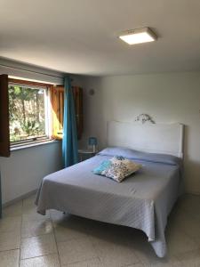 1 dormitorio con 1 cama con colcha blanca y ventana en Scrusciu do Mari, en Butera