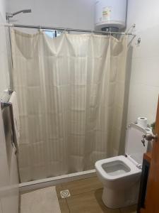 y baño con cortina de ducha y aseo. en Casa en colonia del sacramento, en Colonia del Sacramento