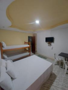 a bedroom with a white bed and a tv at Mini suíte Atitude Maragogi Centro in Maragogi