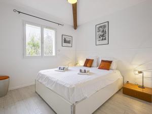 een witte slaapkamer met een groot bed en een raam bij Villa calme avec piscine entre Pays Basque et Sud Landes in Saint-Martin-de-Seignanx