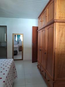 a bedroom with a large wooden cabinet and a mirror at Casa de praia em condomínio exclusivo na Barra de Santo Antônio com piscina in Barra de Santo Antônio